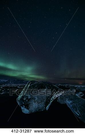 Stock Photo - Northern lights over icy night landscape and Jokulsarlon glacier, Iceland. Fotosearch