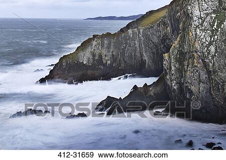 Stock Photo - Ocean and craggy cliffs, Devon, United Kingdom. Fotosearch