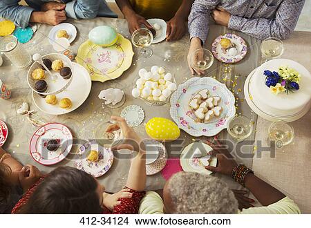 Picture - Overhead view family enjoying Easter desserts and drinking champagne at table. Fotosearch