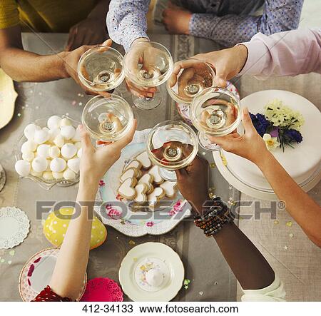 Overhead view friends toasting champagne glasses over Easter desserts View Large Photo Image Stock Image - Overhead view friends toasting champagne glasses over Easter desserts. Fotosearch