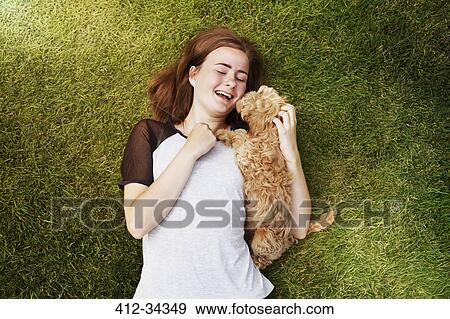 Overhead view happy young woman cuddling affectionate dog in grass View Large Photo Image Stock Photo - Overhead view happy young woman cuddling affectionate dog in grass. Fotosearch