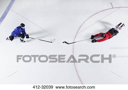 Overhead view hockey players diving for puck on ice View Large Photo Image Stock Photo - Overhead view hockey players diving for puck on ice. Fotosearch