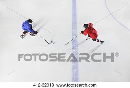Overhead view hockey players going for puck on ice View Large Photo Image Stock Photo - Overhead view hockey players going for puck on ice. Fotosearch