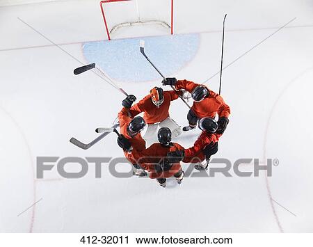 Stock Image - Overhead view hockey team in red uniforms huddling on ice. Fotosearch