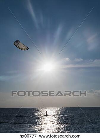 Parasailing on ocean under sunny blue sky View Large Photo Image Stock Photo - Parasailing on ocean under sunny blue sky. Fotosearch