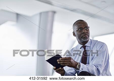 Pensive businessman with journal looking away View Large Photo Image Stock Image - Pensive businessman with journal looking away. Fotosearch