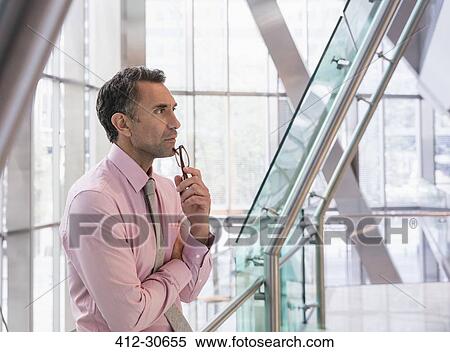 Pensive corporate businessman in modern office lobby View Large Photo Image Stock Photography - Pensive corporate businessman in modern office lobby. Fotosearch