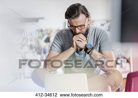 Pensive male design professional working at laptop View Large Photo Image Stock Image - Pensive male design professional working at laptop. Fotosearch