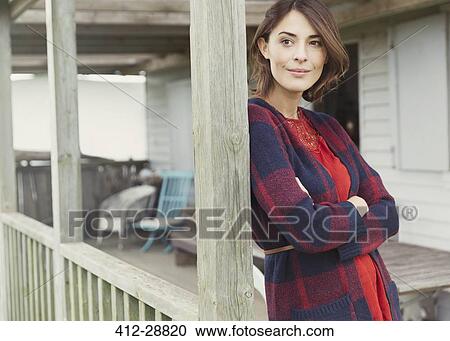 Stock Image - Pensive woman in sweater looking away on porch. Fotosearch