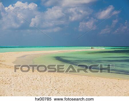 Stock Photography - People in distance walking on tropical beach, Maldives. Fotosearch
