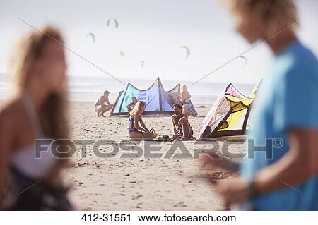 Stock Image - People with kiteboarding equipment on sunny beach. Fotosearch