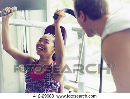 Personal trainer encouraging woman using exercise equipment at gym View Large Photo Image Stock Photo - Personal trainer encouraging woman using exercise equipment at gym. Fotosearch