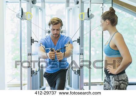 Personal trainer guiding man using cable exercise machine at gym View Large Photo Image Stock Photo - Personal trainer guiding man using cable exercise machine at gym. Fotosearch