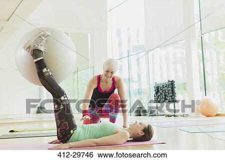 Personal trainer guiding woman with fitness ball between legs View Large Photo Image Stock Photograph - Personal trainer guiding woman with fitness ball between legs. Fotosearch