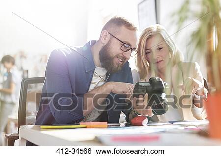 Stock Photograph - Photographer design professionals using SLR camera in office. Fotosearch