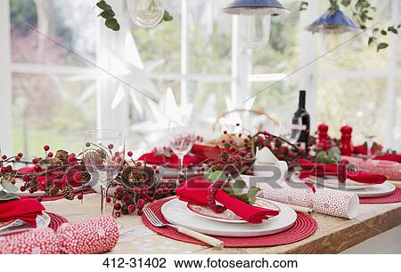 Stock Image - Placesettings and Christmas decorations on dining table. Fotosearch