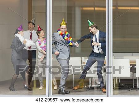 Playful business people in party hats dancing at conference room window View Large Photo Image Stock Photo - Playful business people in party hats dancing at conference room window. Fotosearch