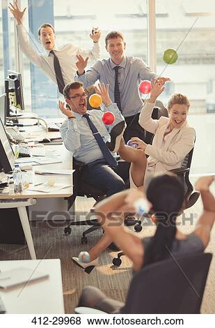 Playful business people throwing colorful plastic balls at each other in office View Large Photo Image Stock Photo - Playful business people throwing colorful plastic balls at each other in office. Fotosearch