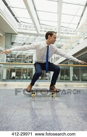 Playful businessman skateboarding in office corridor View Large Photo Image Stock Image - Playful businessman skateboarding in office corridor. Fotosearch