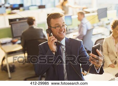 Playful businessman talking on telephone and taking selfie in office View Large Photo Image Stock Photography - Playful businessman talking on telephone and taking selfie in office. Fotosearch