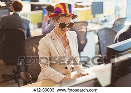 Playful businesswoman wearing silly sunglasses and striped hat at computer in office View Large Photo Image Stock Image - Playful businesswoman wearing silly sunglasses and striped hat at computer in office. Fotosearch