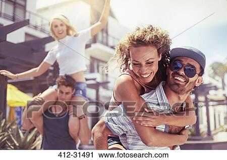 Stock Image - Playful couples piggybacking. Fotosearch
