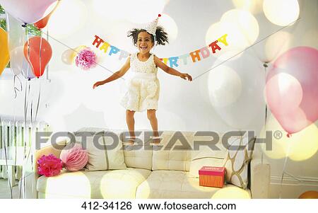 Stock Photograph - Playful girl jumping on sofa. Fotosearch