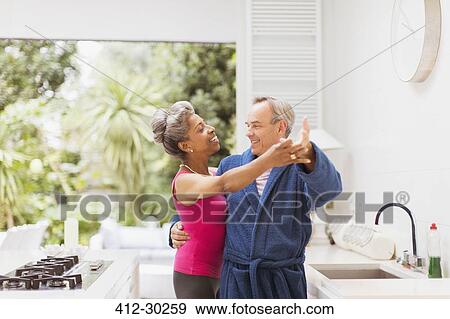 Playful mature couple dancing in kitchen View Large Photo Image Stock Photo - Playful mature couple dancing in kitchen. Fotosearch