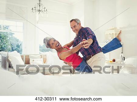 Playful mature couple dancing in living room View Large Photo Image Stock Image - Playful mature couple dancing in living room. Fotosearch