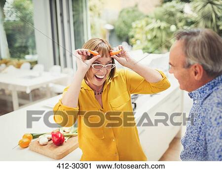 Playful mature woman gesturing carrot horns in kitchen View Large Photo Image Stock Image - Playful mature woman gesturing carrot horns in kitchen. Fotosearch