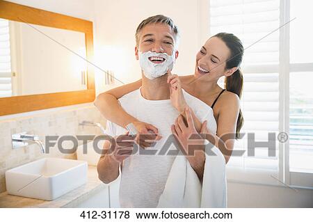 Playful wife wiping shaving cream on husbands face in bathroom View Large Photo Image Stock Photo - Playful wife wiping shaving cream on husbands face in bathroom. Fotosearch
