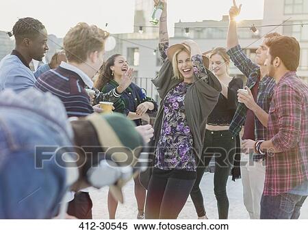 Playful young adult friends dancing at rooftop party View Large Photo Image Stock Photography - Playful young adult friends dancing at rooftop party. Fotosearch