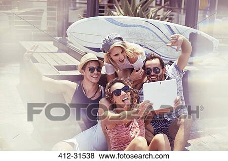 Playful young friends taking selfie in front of surfboard with digital tablet View Large Photo Image Stock Photo - Playful young friends taking selfie in front of surfboard with digital tablet. Fotosearch