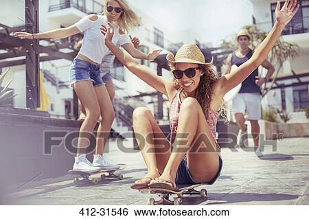 Playful young woman riding skateboard View Large Photo Image Stock Photograph - Playful young woman riding skateboard. Fotosearch