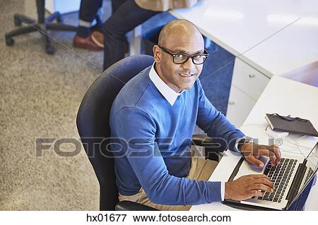 Stock Photo - Portrait businessman working at laptop in office. Fotosearch