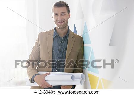 Stock Photography - Portrait confident architect holding blueprints. Fotosearch