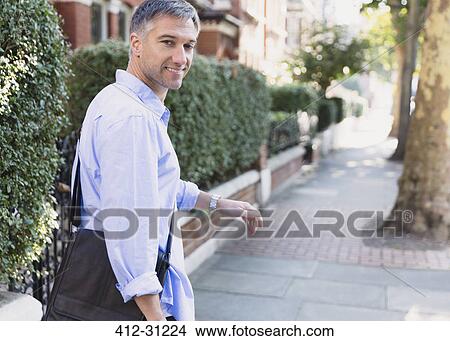 Portrait confident businessman walking and looking back on sidewalk View Large Photo Image Picture - Portrait confident businessman walking and looking back on sidewalk. Fotosearch