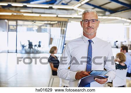 Portrait confident businessman with digital tablet in office View Large Photo Image Stock Photo - Portrait confident businessman with digital tablet in office. Fotosearch