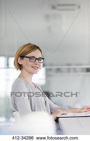 Portrait confident businesswoman at laptop in office View Large Photo Image Stock Photograph - Portrait confident businesswoman at laptop in office. Fotosearch