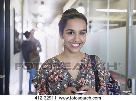 Portrait confident college student with cell phone in corridor View Large Photo Image Stock Image - Portrait confident college student with cell phone in corridor. Fotosearch