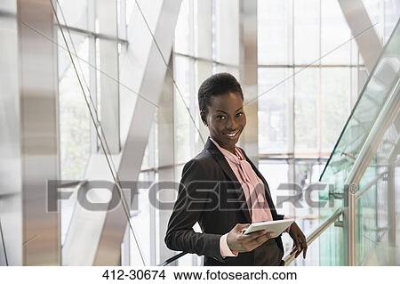 Portrait confident corporate businessman with digital tablet in modern office lobby View Large Photo Image Picture - Portrait confident corporate businessman with digital tablet in modern office lobby. Fotosearch