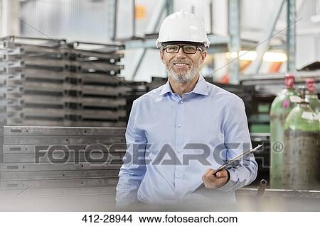 Picture - Portrait confident engineer with clipboard in factory. Fotosearch
