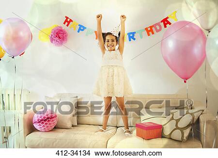 Portrait confident girl with arms raised on sofa at birthday party View Large Photo Image Picture - Portrait confident girl with arms raised on sofa at birthday party. Fotosearch