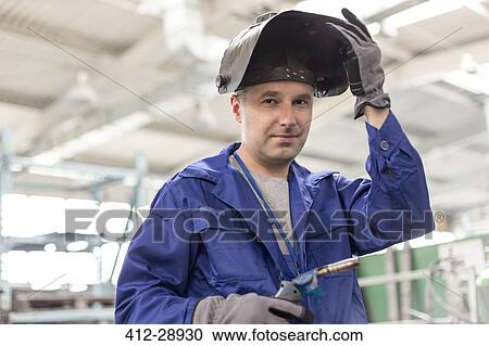 Stock Image - Portrait confident welder with welding torch in factory. Fotosearch