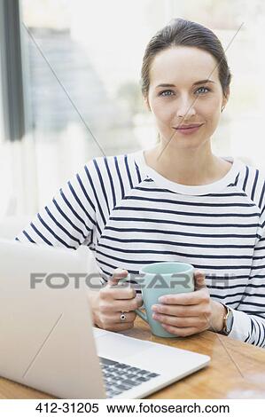 Stock Photography - Portrait confident woman drinking coffee at laptop. Fotosearch