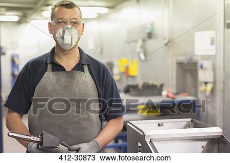Stock Image - Portrait confident worker wearing protective mask in steel factory. Fotosearch