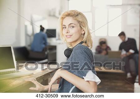 Stock Photo - Portrait confident young female college student with headphones at laptop. Fotosearch