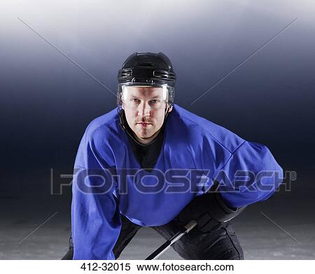 Stock Photography - Portrait determined hockey player in blue uniform on ice. Fotosearch