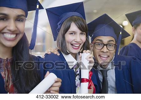 Stock Image - Portrait enthusiastic college graduates in cap and gown posing with diploma. Fotosearch