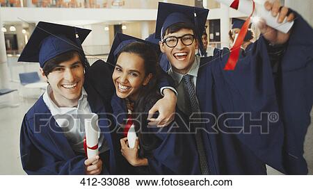 Stock Photo - Portrait enthusiastic college graduates in cap and gown with diplomas. Fotosearch